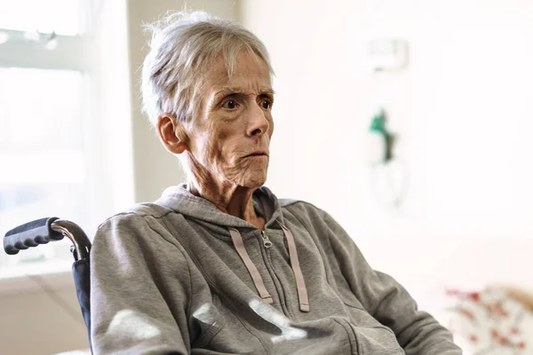 Хвора, літня старша жінка в лікарняній кімнаті з інвалідним кріслом — стокове фото