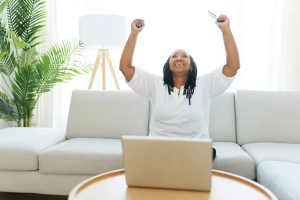 Photo de jolie femme noire utilisant un ordinateur portable à la maison canapé et acheter quelque chose sur le web — Photo