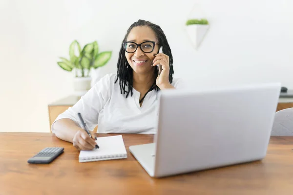 Black woman using computer in modern kitchen interior — Photo