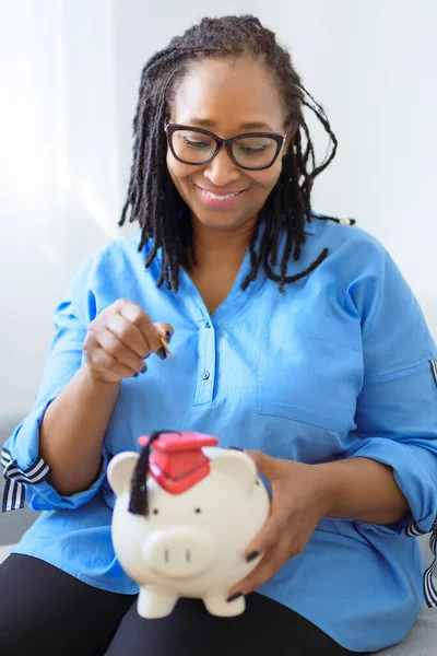 Beautiful black woman holds a pink piggy bank representing savings and retirement — Stock fotografie