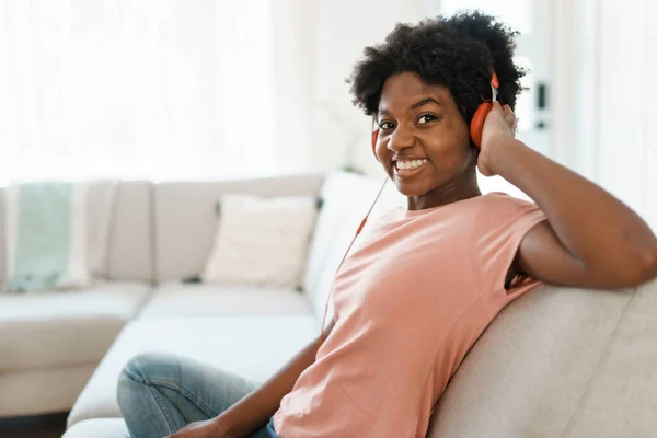 Happy african american woman with headphones listening to music at home — Stock Photo, Image