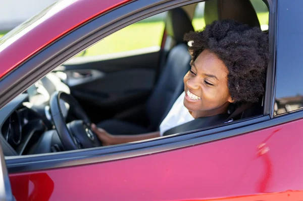 Young black woman sit on is first red car — Photo