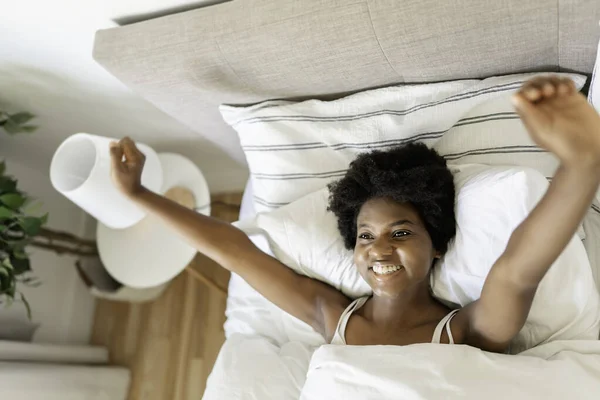 Beautiful young African woman in tank top lying in bed — Fotografia de Stock