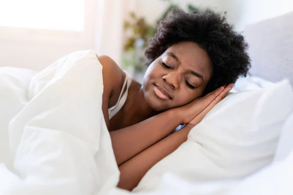 Beautiful young African woman in tank top lying in bed sleeping — Fotografia de Stock