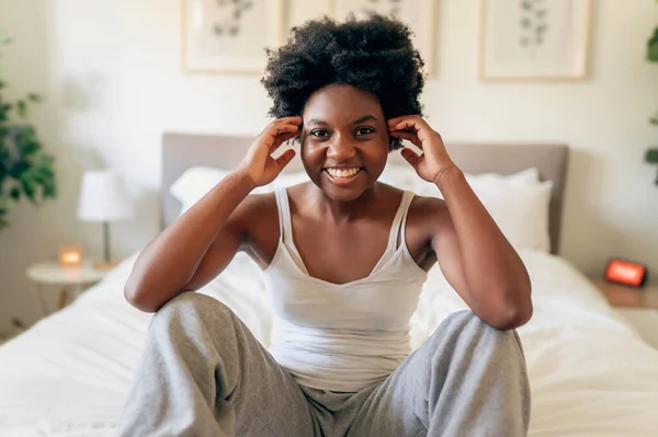 Beautiful young African woman in tank top sit on bedroom — Stockfoto