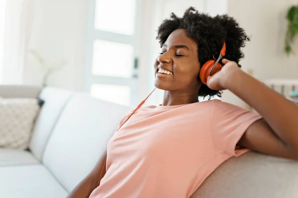 Happy african american woman with headphones listening to music at home — Stock Photo, Image
