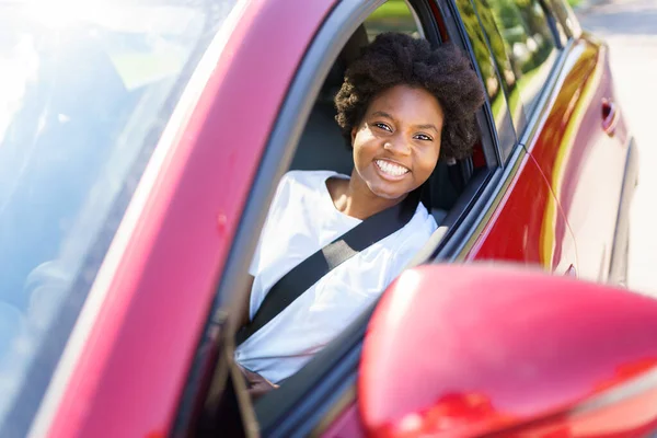 Young black woman sit on is first red car — Photo