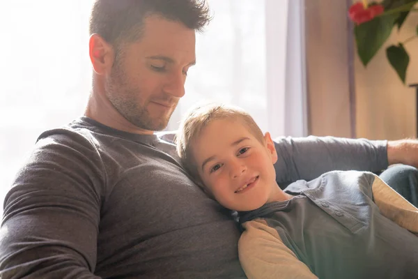 Sitter far og sønn i sofaen hjemme – stockfoto