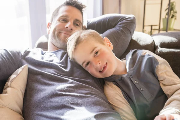 Отец и сын сидят дома на диване — стоковое фото
