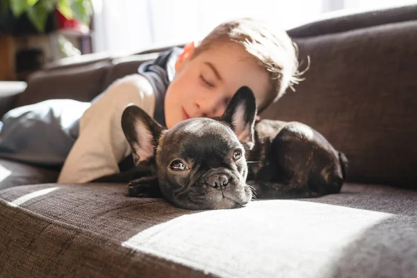 Menino com Bulldog francês Filhote de cachorro no sofá — Fotografia de Stock