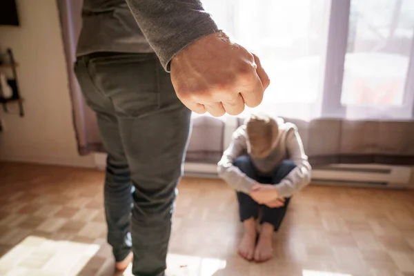 Sad child boy sit on the floor with father in front of him with hard look and close fist — Fotografia de Stock