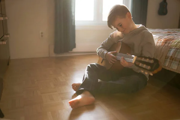A Cheerful Caucasian boy playing guitar on his bedroom — стоковое фото