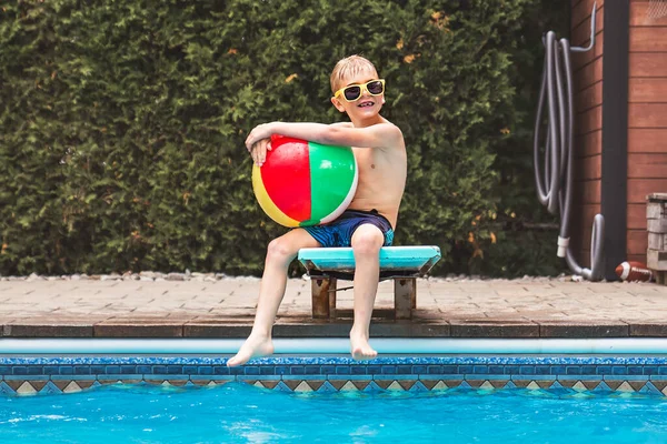 Child boy having fun in Pool on the summer time sit on springboard —  Fotos de Stock
