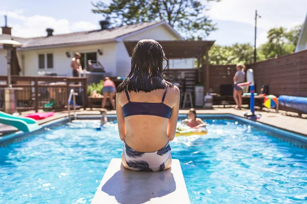 Child girl having fun in Pool on the summer time sit on springboard —  Fotos de Stock