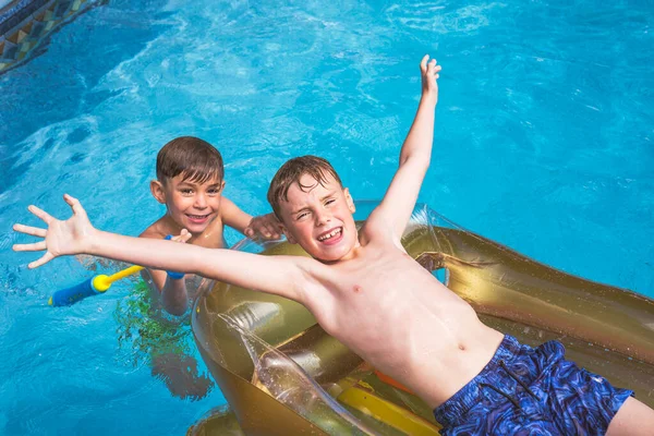 Dos hermanos chicos divirtiéndose en la piscina en el verano —  Fotos de Stock