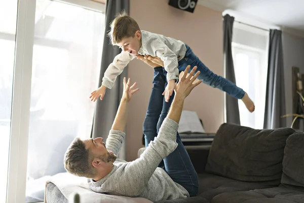 Father or Godfather having fun on the living room sofa At Home flying like a plane — Photo