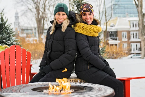 Dos amigos en abrigos de invierno sentados fuego en el bosque — Foto de Stock