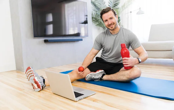 Attractive Fit man Exercise at home on the living room with apple on hand — Stock Fotó