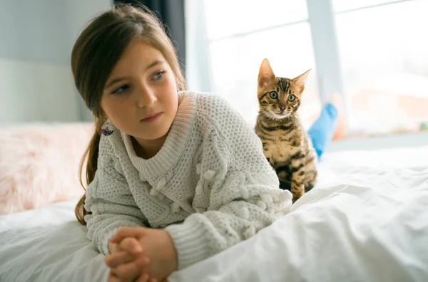 Bengal katt i sängen rum med barn flicka — Stockfoto