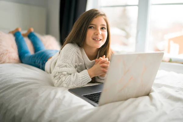 Дитяча дівчина з комп'ютерами на ліжку вдома — стокове фото