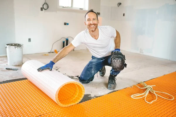 Hombre trabajador instalar naranja rollo membrana impermeabilización en el suelo — Foto de Stock