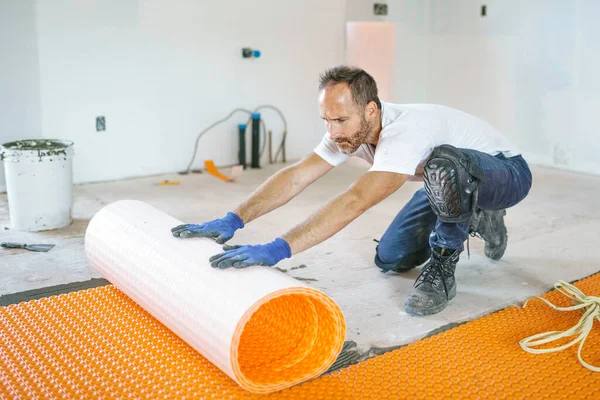 Man worker install orange roll membrane waterproofing on the floor — Stockfoto