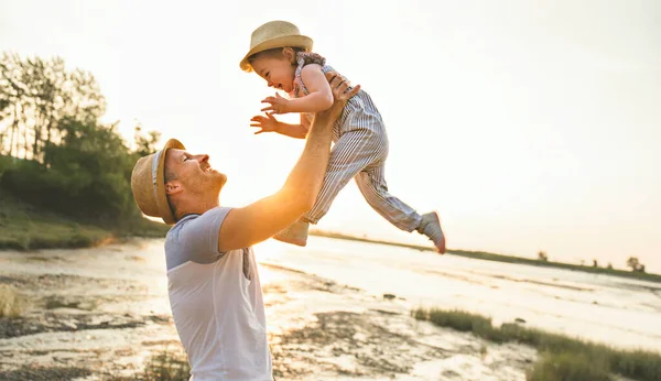 Otec se bavte s dítětem na pláži při západu slunce — Stock fotografie