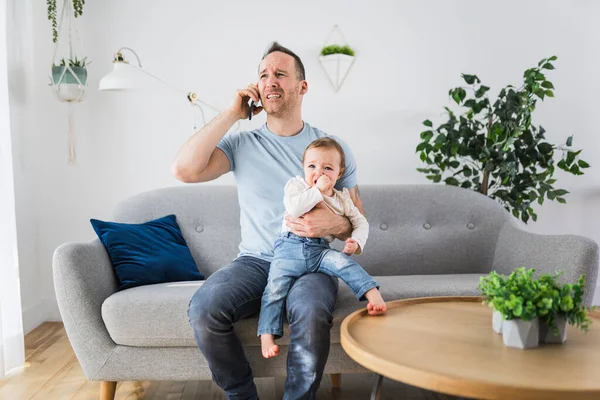 Man holding a screaming baby the father call help on the phone