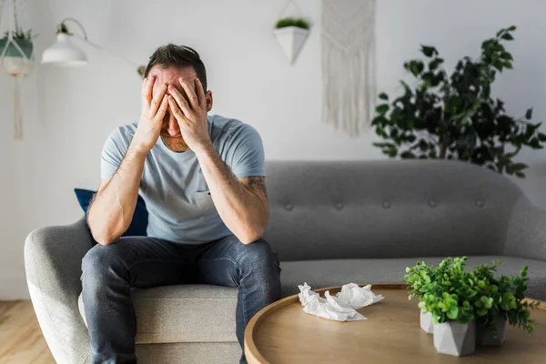 Frustrated handsome man with problem sitting on the couch at home with tissue on the front — Stock Photo, Image