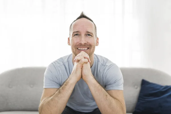 Smilling man wearing casual shirt prayer sitting on couch — ストック写真