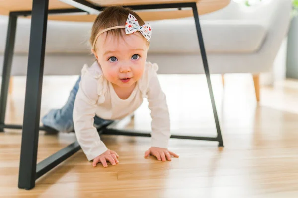 Portrait of a baby girl having fun underneath the table in the living room — Photo