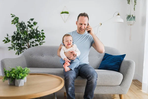 Man holding a screaming baby the father call help on the phone