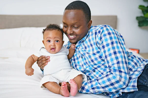 Feliz joven africano jugando con su pequeño bebé mientras yacía en la cama — Foto de Stock