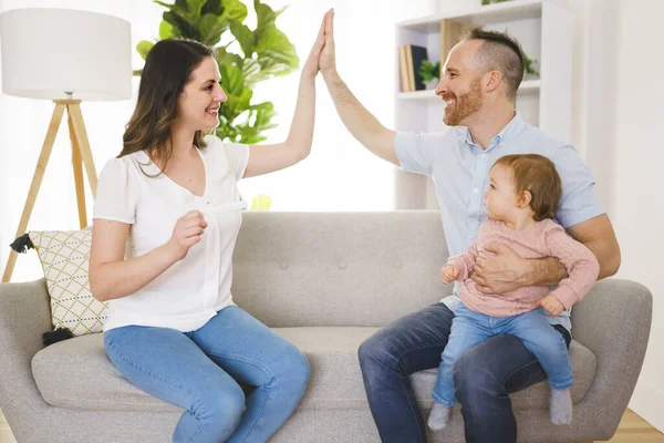 Сім'я щаслива з тестом на вагітність зі своєю збудженою дружиною сидить на дивані вдома . — стокове фото