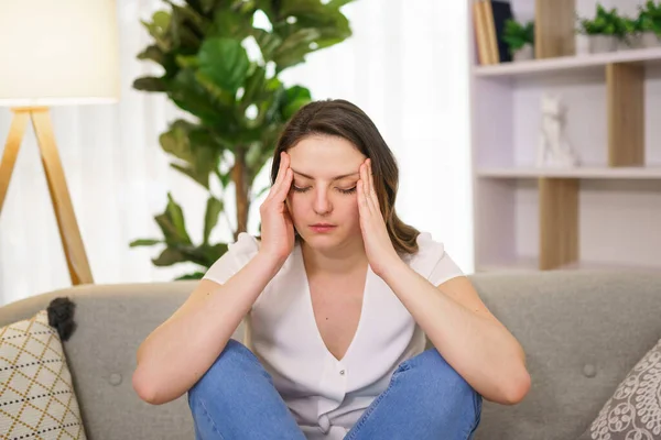 Woman feels pain in head sit on sofa — Stock Photo, Image