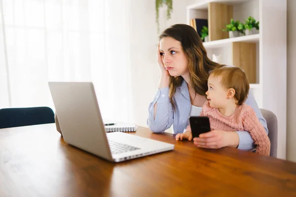 Triste e frustrada mãe na cozinha home office com computador e sua filha — Fotografia de Stock