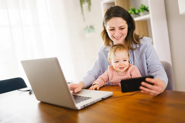 Mamma i köket hemmakontor med dator och laptop hemma med sin dotter — Stockfoto