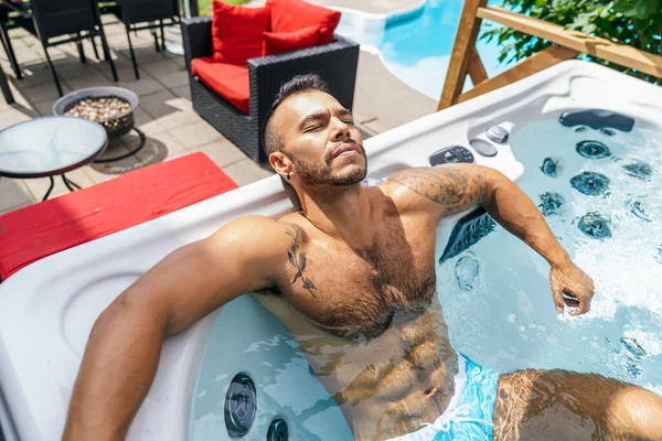 sexy mexican man relaxing in hot tub on summer season