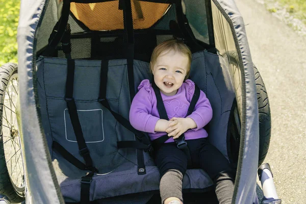 Little and very beautiful girl sitting on a jogging stroller — Stock Photo, Image