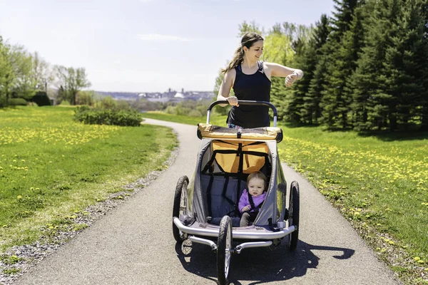 Vacker ung familj med barn i joggingvagn som springer utomhus under sommarsäsongen — Stockfoto