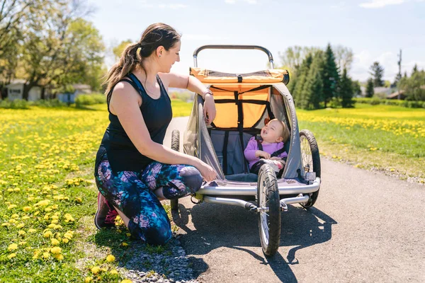 Beautiful young family with baby in jogging stroller running outside in summer season — Stock fotografie