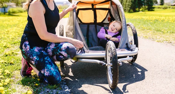 Beautiful young family with baby in jogging stroller running outside in summer season — Stockfoto