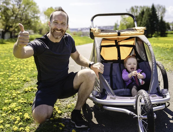 Man with baby in jogging stroller running outside in summer season — Stockfoto