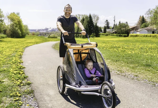 Man with baby in jogging stroller running outside in summer season — Stock Photo, Image