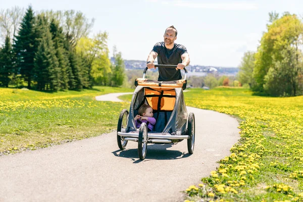 Man med barn i joggingvagn som springer utomhus under sommarsäsongen — Stockfoto