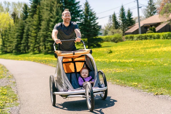 Man with baby in jogging stroller running outside in summer season — Stock Fotó
