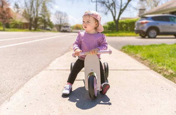 Маленька дівчинка грає з велосипедом на вуличному фоні — стокове фото