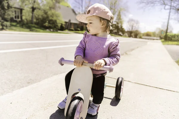 Liten flicka lek med cykel i gatan bakgrund — Stockfoto