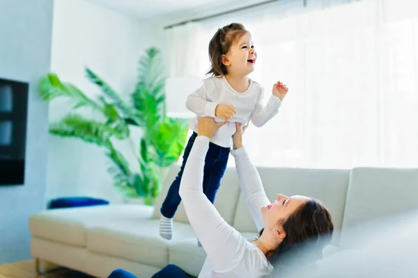 Mother with her daughter having fun in living room at home — стокове фото