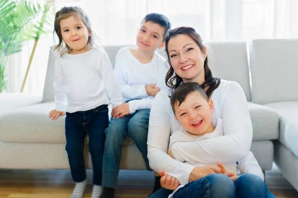 Madre cariñosa con niños disfrutando del tiempo juntos en el sofá de casa —  Fotos de Stock